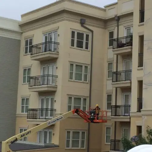 A man on a cherry picker working in front of a building.