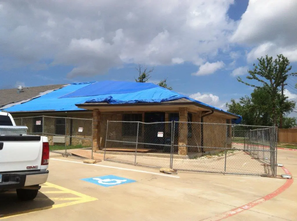 A blue tarp covers the roof of an animal shelter.