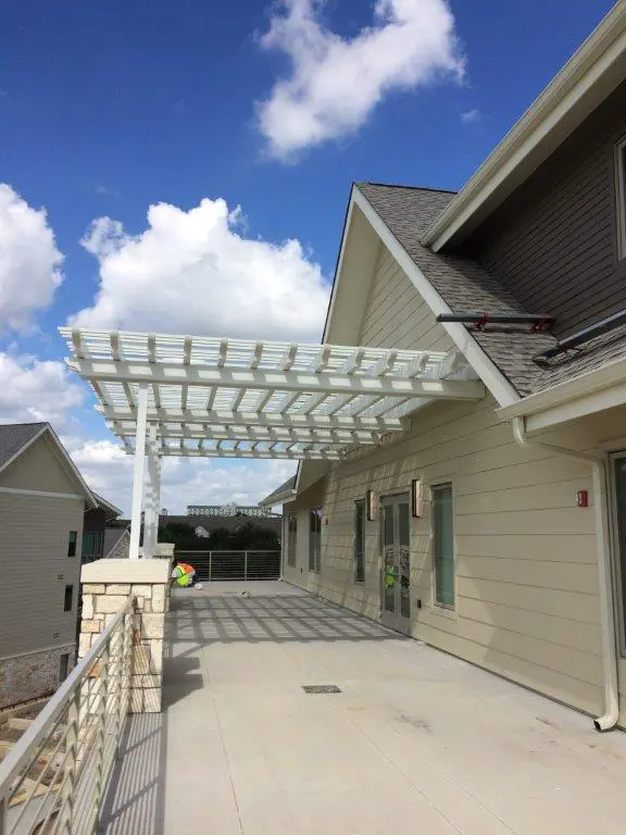 A large white pergola on the side of a house.